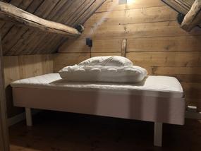 En enkeltseng p&aring; hemsen som har gamle trevegger