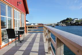 Stor terrasse over vannet med utsikt over Hamn&oslash;y havn. To stoler og et bord.