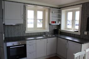 Kj&oslash;kken med komfyr, stekeovn, kj&oslash;leskap og oppvaskmaskin. To vinduer med utsikt over Hamn&oslash;y havn.