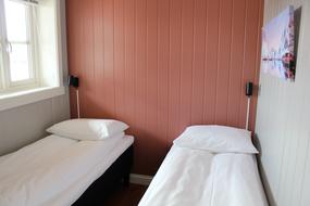 Lite soverom med to separate senger. Vindu p&aring; h&oslash;yre vegg ut mot hamnen og nattlys over senger 