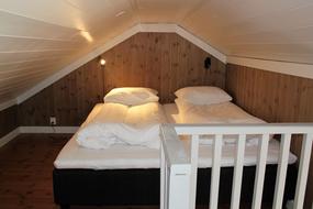 Soverom p&aring; loft med to separate senger med nattlys over. 