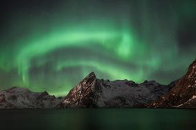 Gr&oslash;nt nordlys over Reinefjorden og fjellet Olstinden.