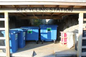 Milj&oslash;stasjon med separate s&oslash;ppelb&oslash;tter for plastikk, papir/kartonger, glass/metall, matavfall, restavfall og panteflasker. 